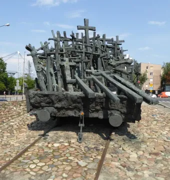 Monument to the Fallen and Murdered in the East, a dark sculpture shaped like a railway flatcar covered with crosses and beam-like forms