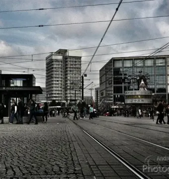 The World Clock at Alexanderplatz in Berlin, surrounded by pedestrians and city buildings.