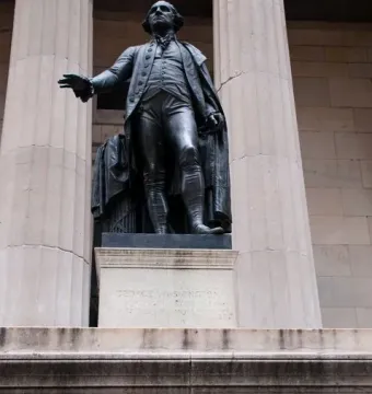 Statue of George Washington on a stone pedestal with engraved text on the base.