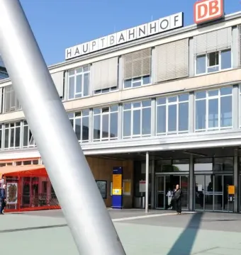 Himmelsstürmer sculpture rising in front of Kassel Hauptbahnhof with the station building in the background.