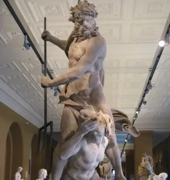 Neptune and Triton marble sculpture showing Neptune holding a trident over a kneeling Triton in a museum hall.