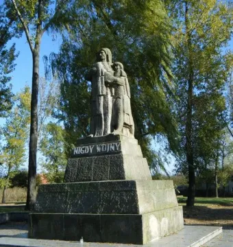 Stone monument War Never Again showing three stylized figures of an adult man, woman, and child on a tiered base.