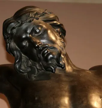 Upper body of Bernini\'s Corpus bronze sculpture showing Christ with a crown of thorns, head tilted and eyes closed.