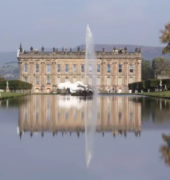 Emperor Fountain rising from a reflecting pool in front of a grand historic mansion