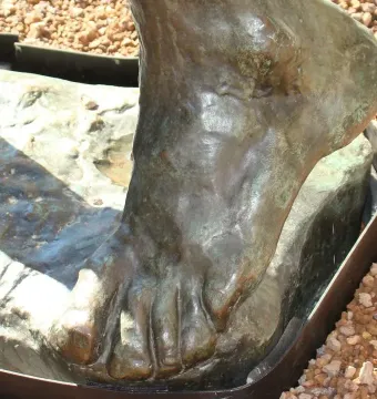 Close-up of the bronze foot detail of Jean de Fiennes, with textured patina and a rough base.