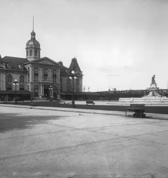La Fermière fountain beside a large stone market building and paved plaza.
