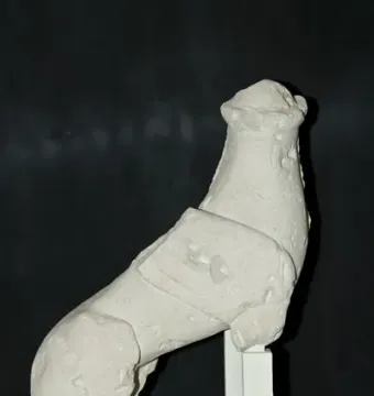 Sphinx of Agost sculpture with a human head and reclining animal body on a white stand.