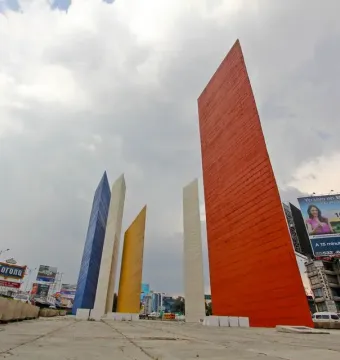 Torres de Satélite with five brightly colored geometric pillars rising against a cloudy sky.