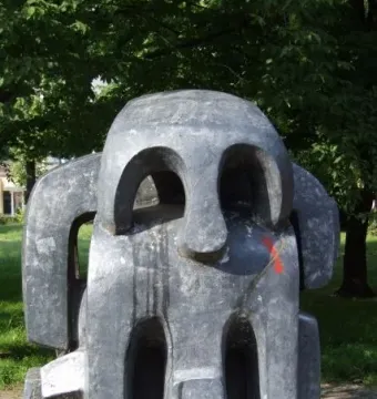 Treblinka memorial abstract dark gray sculpture with carved openings and a red mark on the side