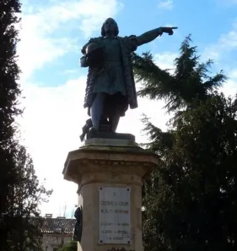 Monument to Columbus: a bronze-toned statue of a man holding a globe and pointing outward on a tall stone pedestal.
