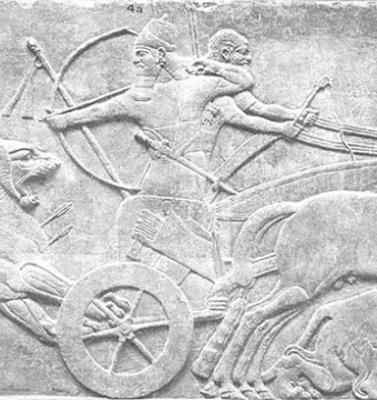 Lion Hunt of Ashurbanipal relief showing a chariot archer shooting at a charging lion, with wounded lions and armed attendants nearby.