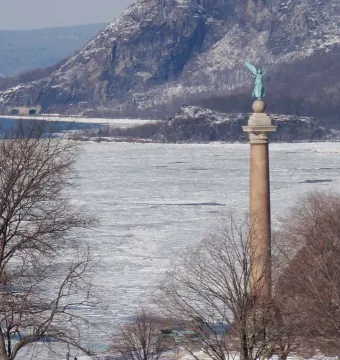 Battle Monument at West Point rising above a frozen river with snowy mountains in the background