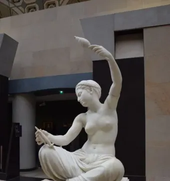 Jeune fille de Mégare, a seated marble female statue holding a spindle and a conical object