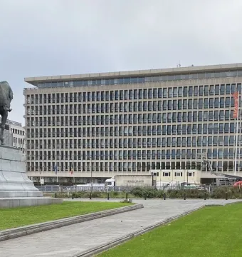 Leopold II equestrian statue on a stone plinth beside a large office building in Brussels.
