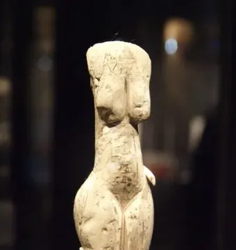 Venus of Eliseevichi figurine with prominent breasts and hips on a white pedestal