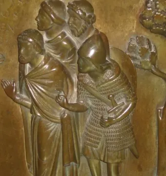 Bronze relief panel from the Baptismal Font at St Bartholomew\'s Church showing four male figures, including one in chainmail with a sword.