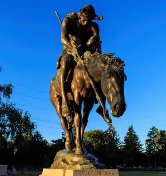 End of the Trail bronze sculpture showing a slumped rider on a lowered horse atop a stone base.