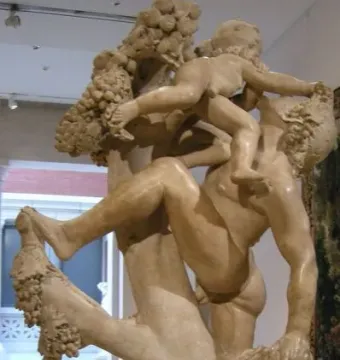 A marble sculpture of A Faun Teased by Children showing a muscular faun with children and grapevines entwined around him.