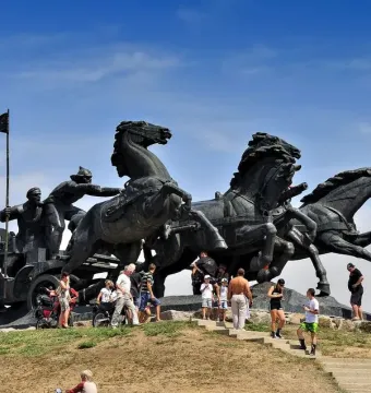 Legendary Tachanka bronze monument with four horses pulling a cart and figures, including one holding a flag.