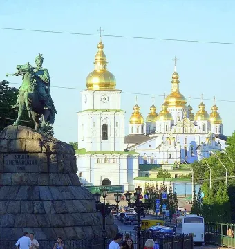 Monument to Bohdan Khmelnytsky on horseback with a cathedral and golden domes in the background.