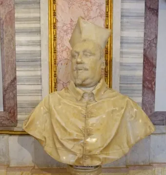 Marble bust of Cardinal Scipione Borghese wearing a clerical hat and buttoned cape, displayed on an ornate pedestal.