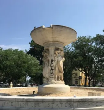 Dupont Circle Fountain with graffiti on one of the sculpted figures and a pigeon perched on top.