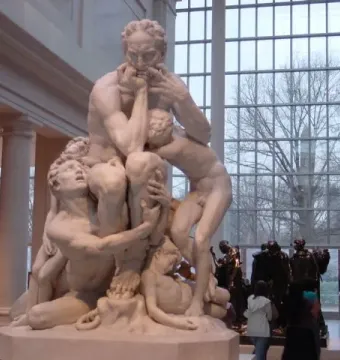 Ugolino and His Sons, a white marble sculpture of a man surrounded by several children in a museum hall.