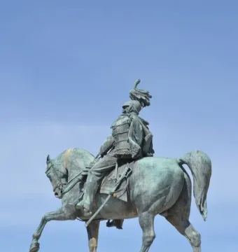 Victor Emmanuel II equestrian statue in bronze atop a stone pedestal against a blue sky.