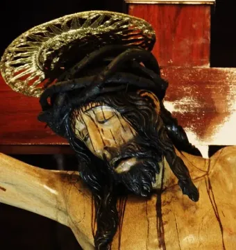 Close-up of Cristo de La Laguna showing the bowed head, closed eyes, crown of thorns, and gilded halo of the wooden crucifix.