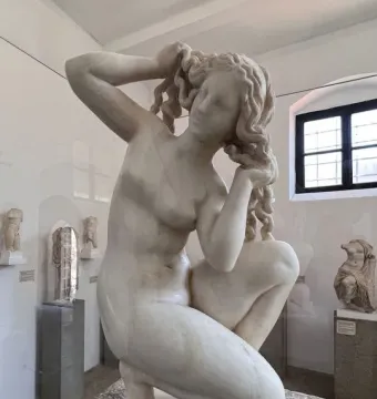 Crouching Venus marble sculpture of a crouching nude woman adjusting her hair in a museum