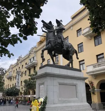Francisco Pizarro equestrian statue mounted on a tall stone pedestal, with a floral wreath at its base.