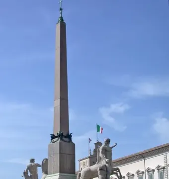 Horse Tamers statues flanking the Quirinal obelisk beneath a blue sky.