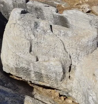 The Kouros of Apollonas, a rough-hewn stone head and upper torso carved from the rock in a quarry setting.