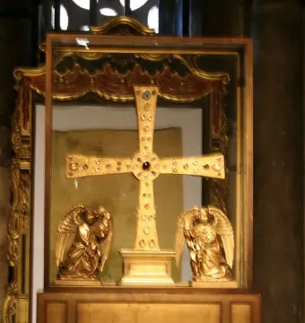 The Cross of the Angels, a jeweled golden cross displayed in a glass case with kneeling angel figures beside it.