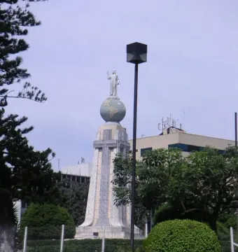 Divino Salvador del Mundo monument with a white statue atop a blue-green globe in a landscaped area