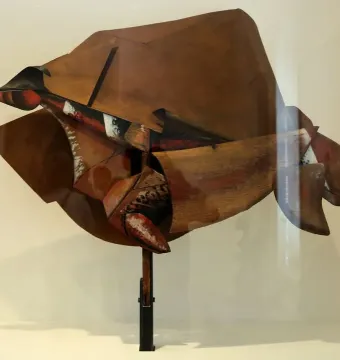 Dynamism of a Speeding Horse + Houses sculpture with angular brown, red, black, and white planes on a dark stand.
