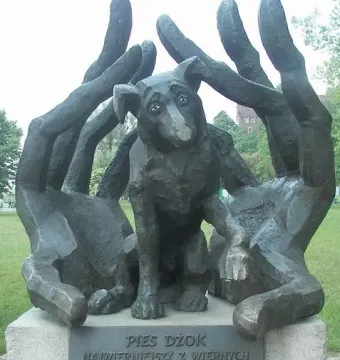 Monument to Dog Jock bronze sculpture of a dog nestled in large human hands on a stone base.