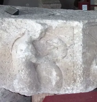 Relief carving on the Pilier d\'Yzeures-sur-Creuse showing two figures on a weathered stone block, with the right figure holding a bow or staff.
