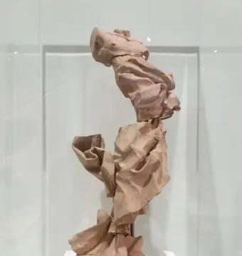 Terracotta model for Bernini’s Saint Longin, shown in stacked, crumpled forms inside a display case on a white pedestal.
