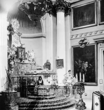 Alexander Nevsky reliquary displayed on a stepped dais in a grand hall with columns and framed paintings.