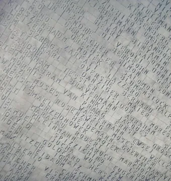 Hailfingen-Tailfingen Memorial name wall covered with hundreds of engraved names in a diagonal grid.