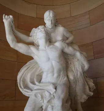 Mercury and Psyche sculpture showing a muscular male figure lifting a draped female figure against a curved stone wall.