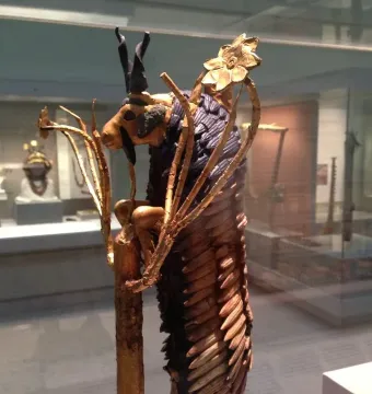 Ram in a Thicket sculpture showing a golden ram standing on hind legs with dark horns and a stylized golden thicket.