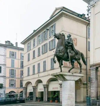 Regisole bronze equestrian statue on a stone pedestal in a cobblestone piazza in Pavia.
