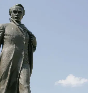 Taras Shevchenko Memorial bronze statue of a man in a long coat against a blue sky
