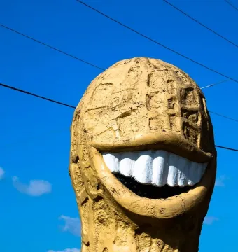 The Jimmy Carter Peanut Statue with a wide grinning mouth and white teeth against a blue sky.