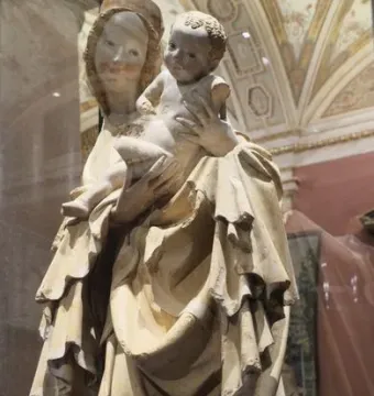 Krumlov Madonna sculpture of a woman holding a child, with flowing carved robes and traces of color on their faces.