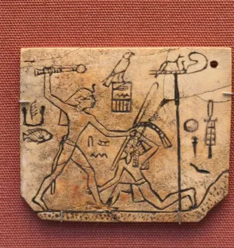 MacGregor plaque showing a carved ivory tablet with a figure raising a mace over a kneeling figure, surrounded by hieroglyphs and symbols.