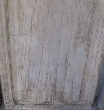 Lower section of the Tomb of Giovanni Crivelli showing a carved robed figure and weathered Latin inscriptions on the stone frame.
