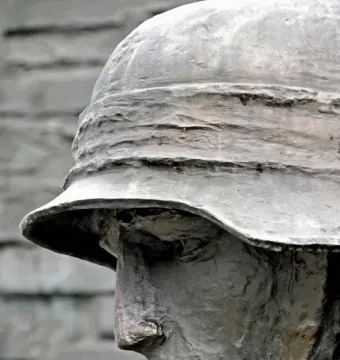 Close-up of the Warsaw Uprising Monument showing a weathered bronze soldier’s profile in a helmet.